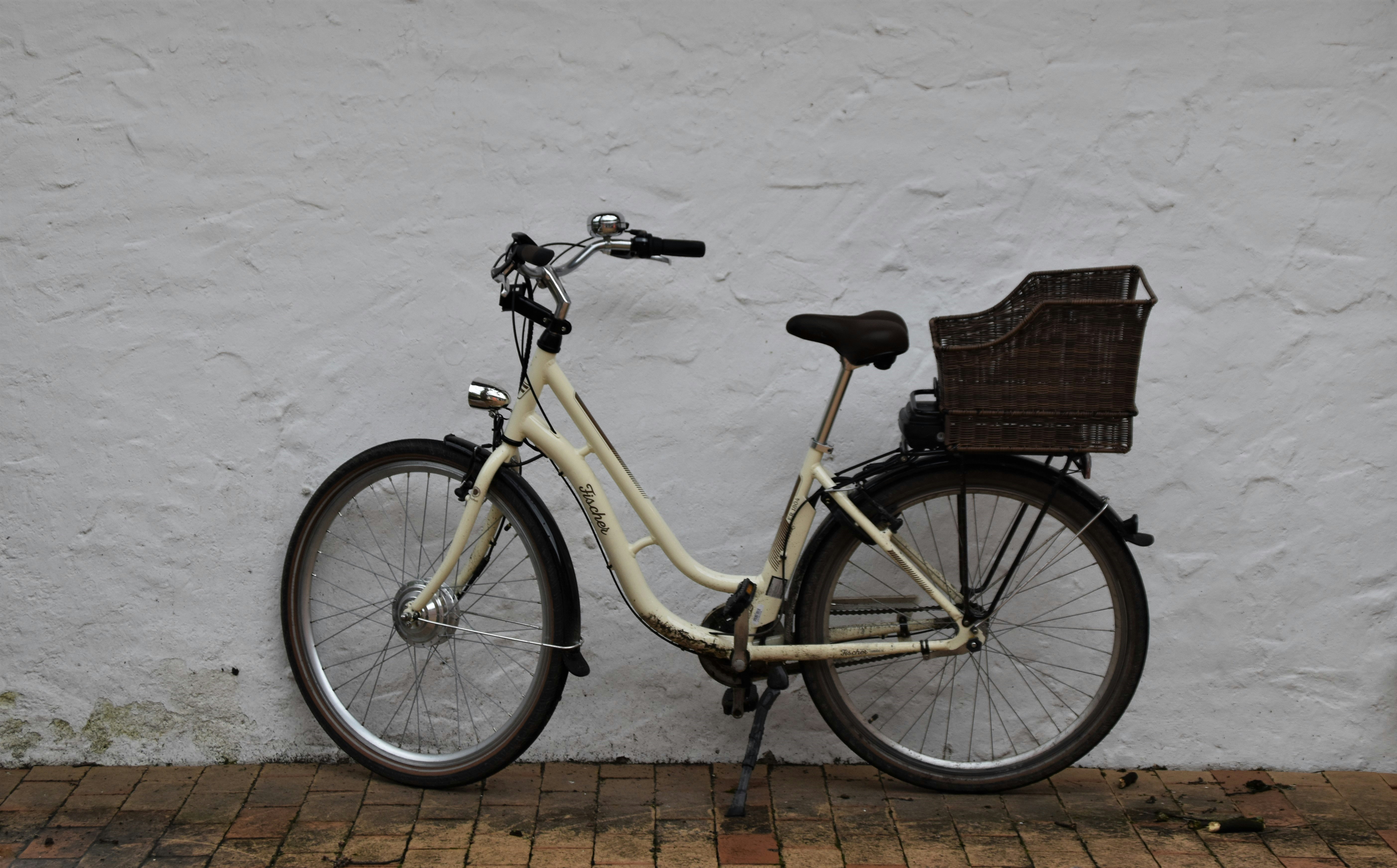 yellow city bicycle with brown woven basket on top