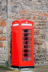 red telephone booth on brown brick wall