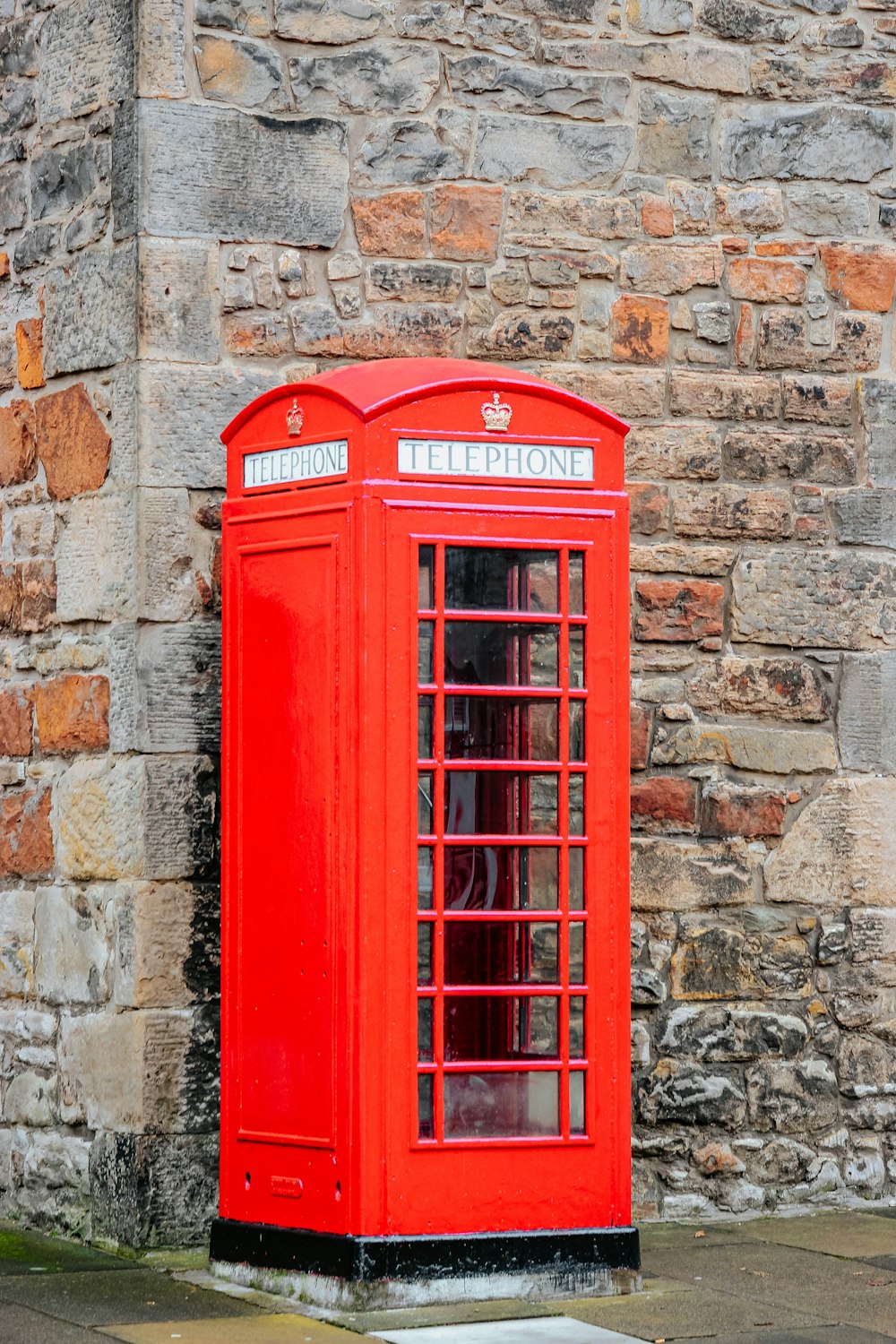 red telephone booth on brown brick wall