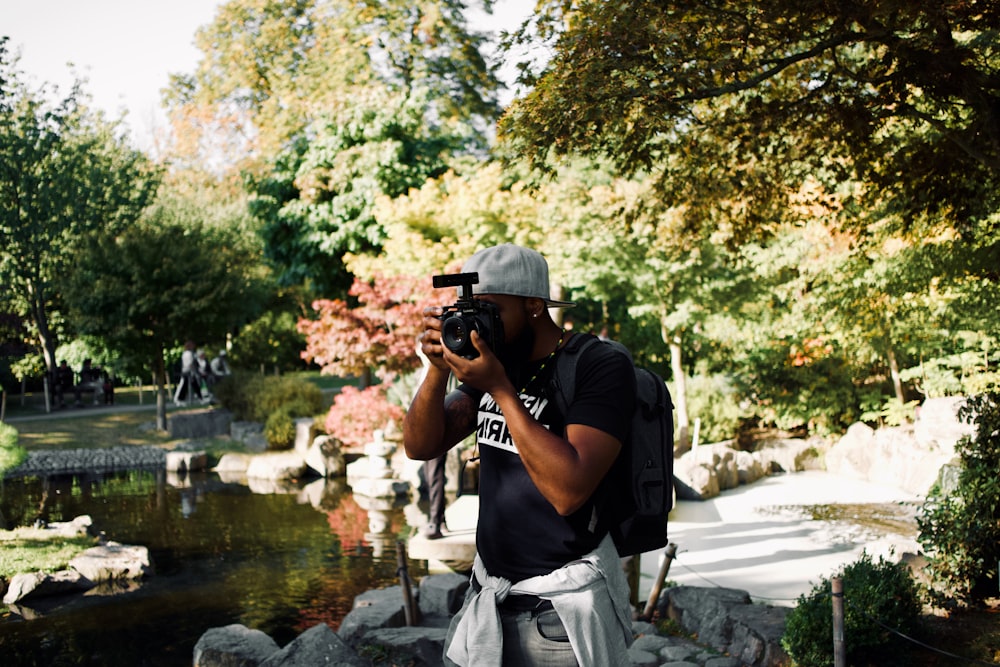 man in black t-shirt and gray pants holding black dslr camera