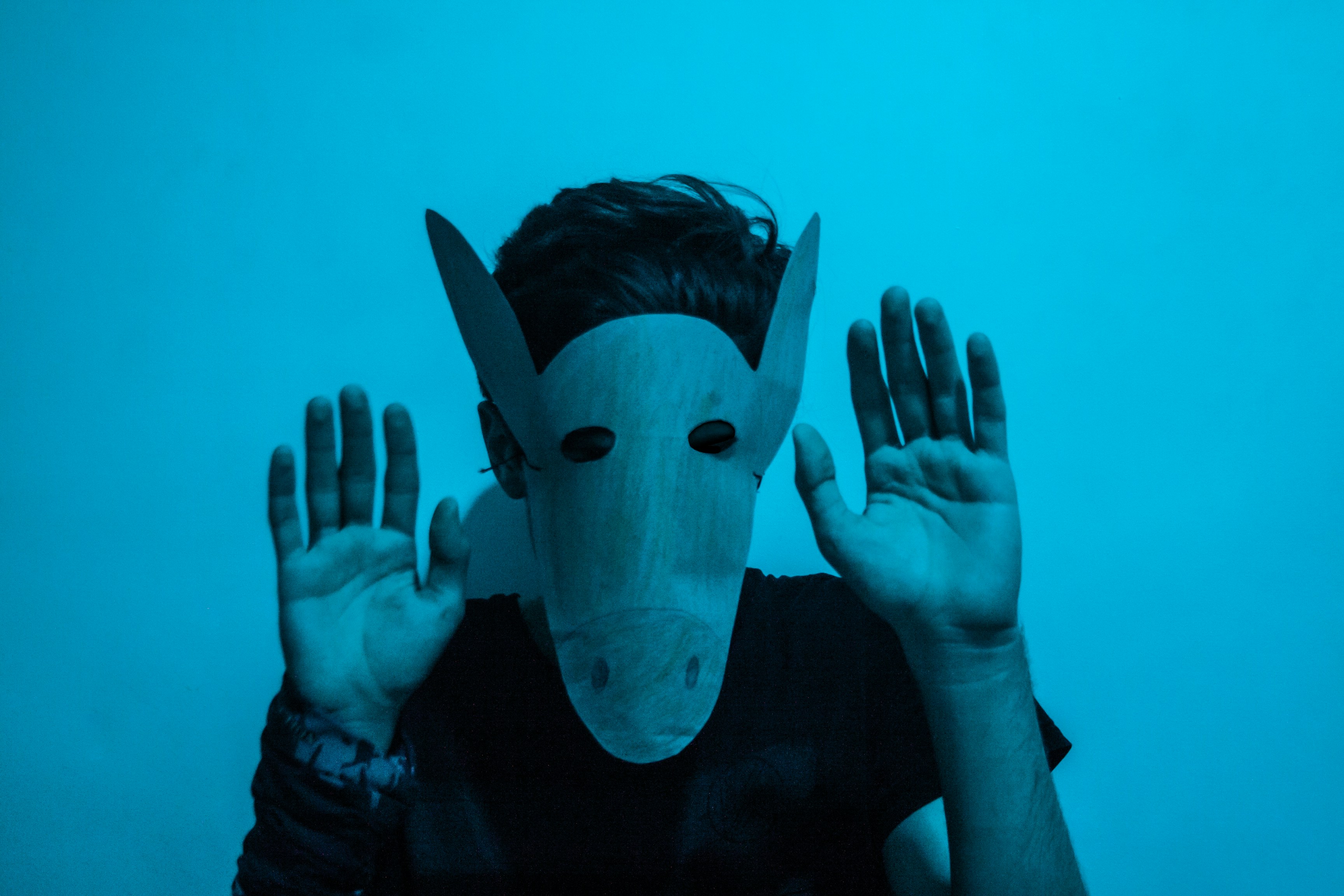 man in black long sleeve shirt covering his face with white mask