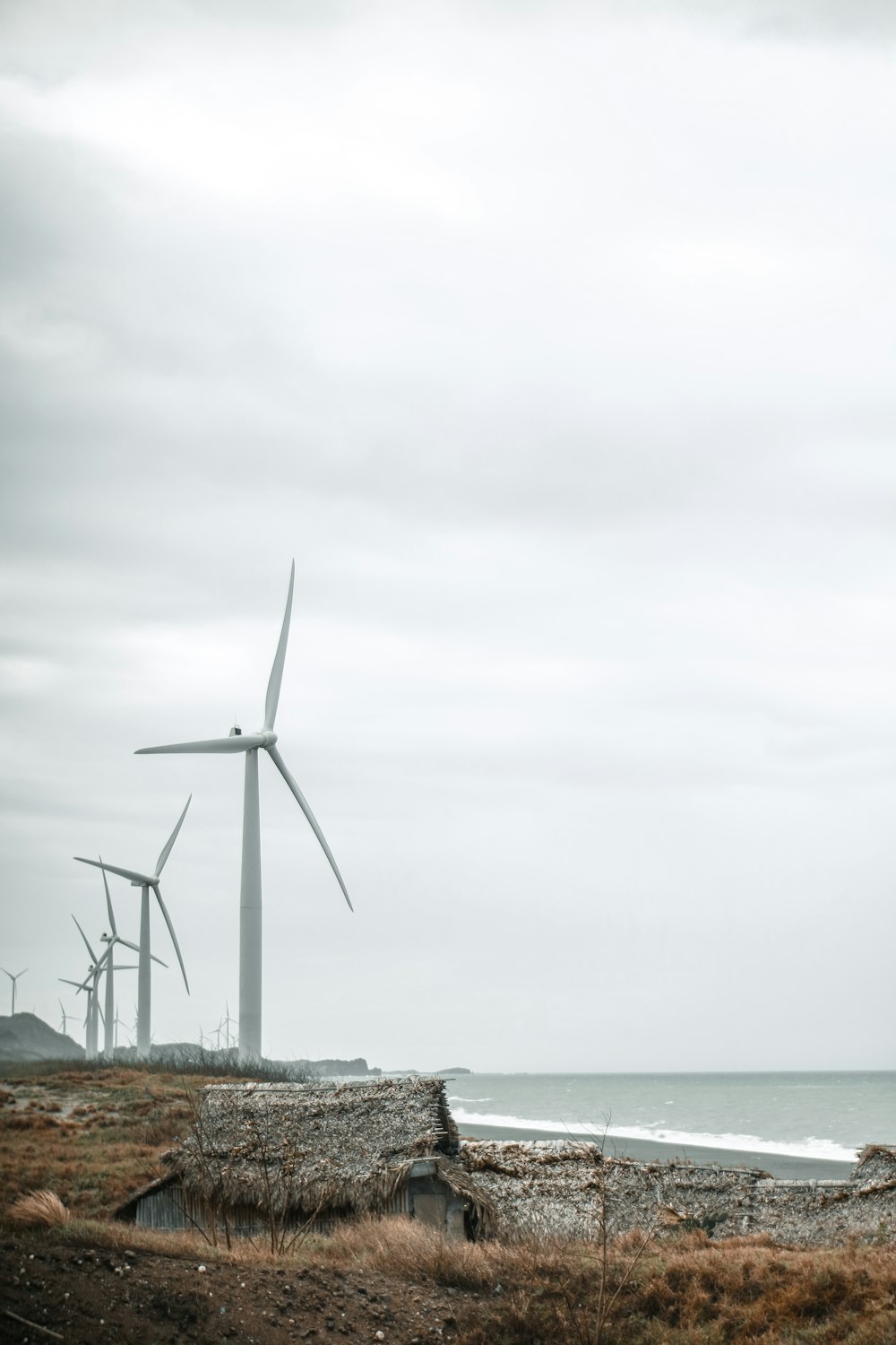 wind turbine on rock formation near body of water during daytime