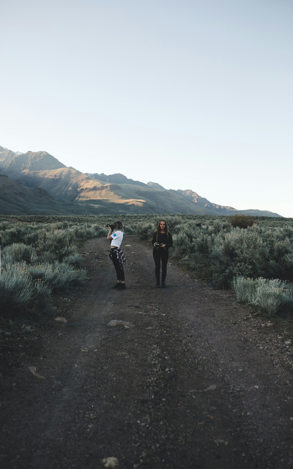 2 person walking on dirt road during daytime