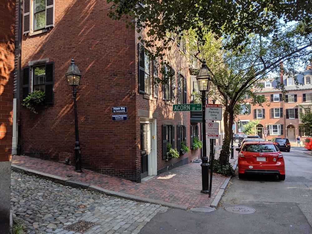 red car parked beside brown brick building