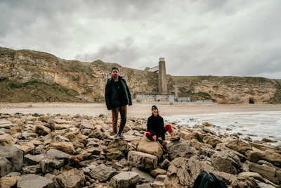 man in black jacket standing on rock near body of water during daytime