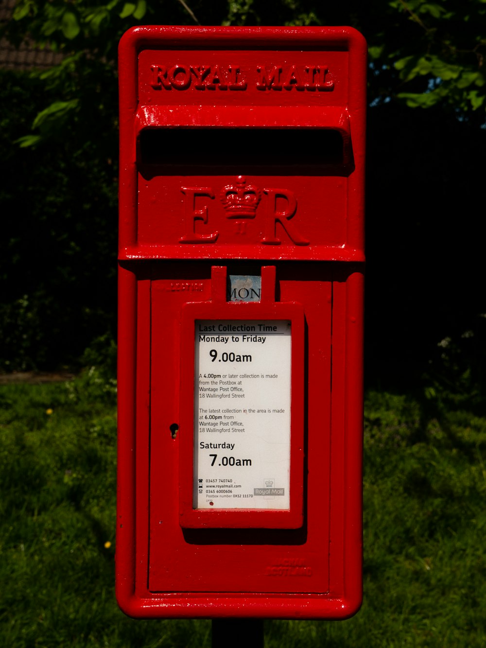 Buzón de correo rojo en campo de hierba verde