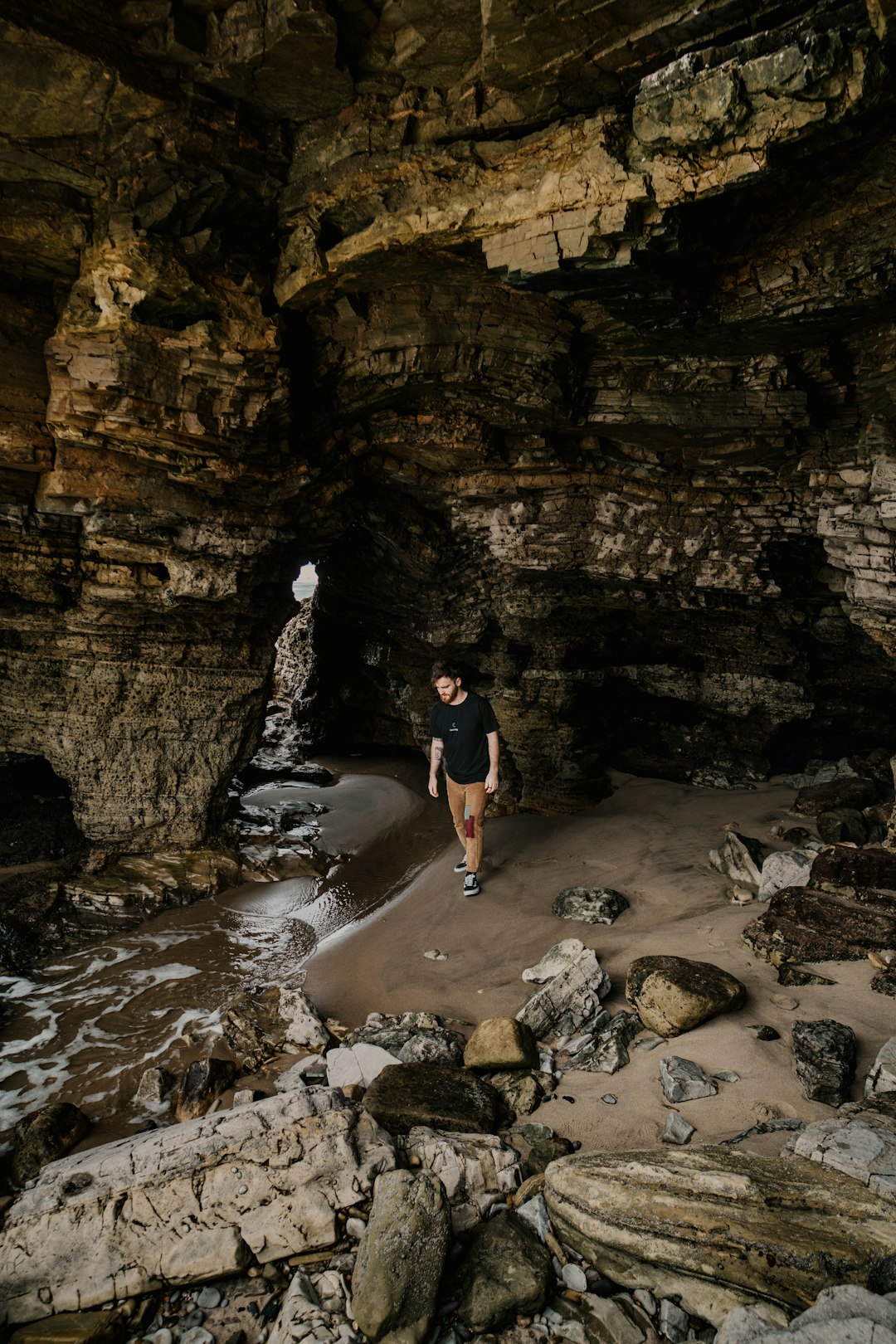 man in black t-shirt and black shorts standing on rocky river