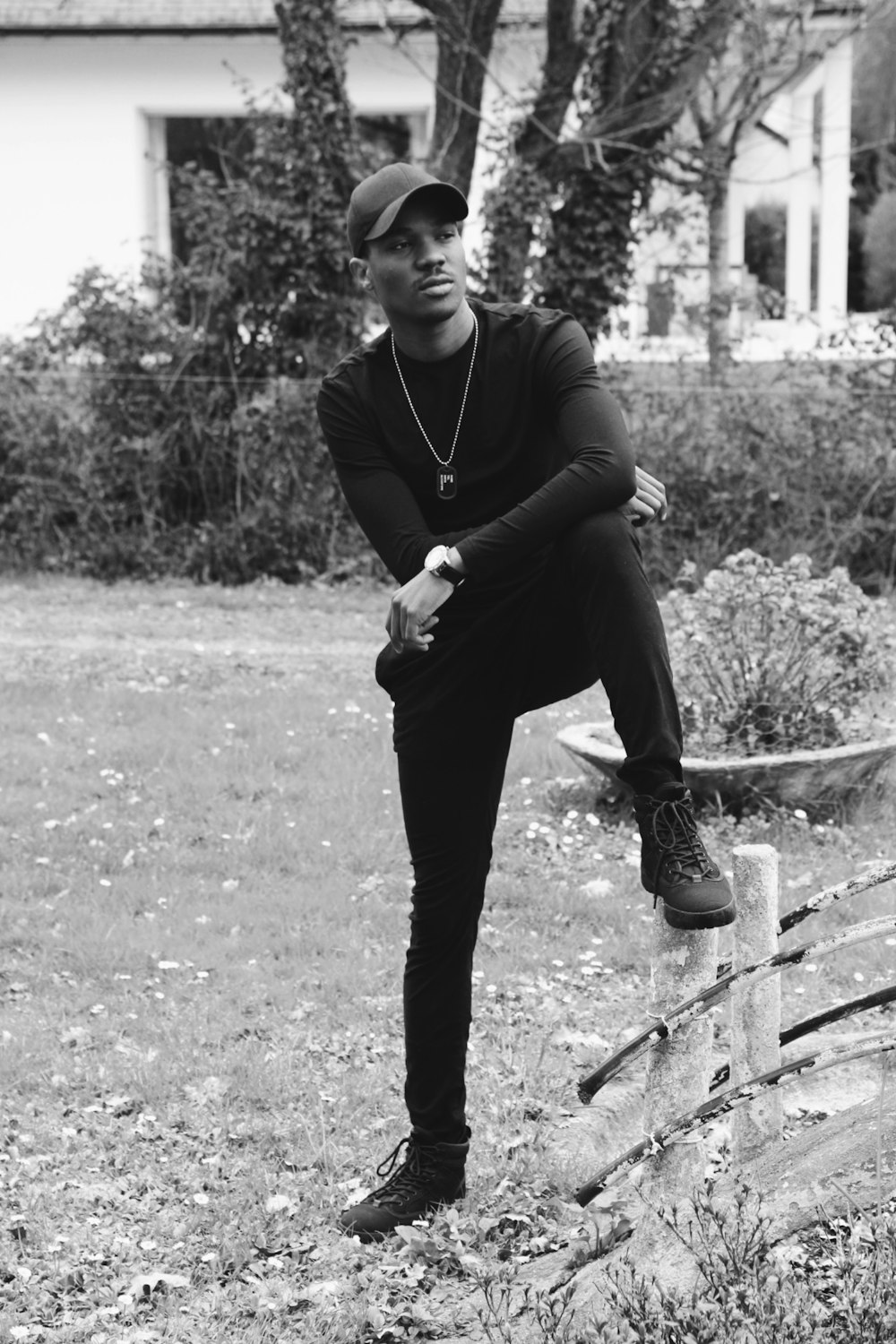 man in black long sleeve shirt and black pants standing on concrete fence