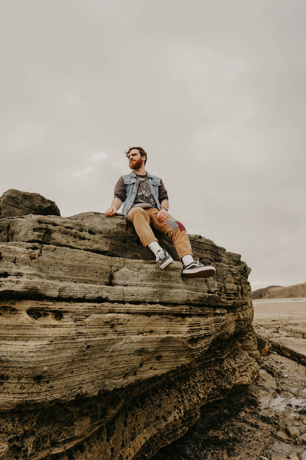 man in blue and red plaid dress shirt sitting on brown rock formation during daytime
