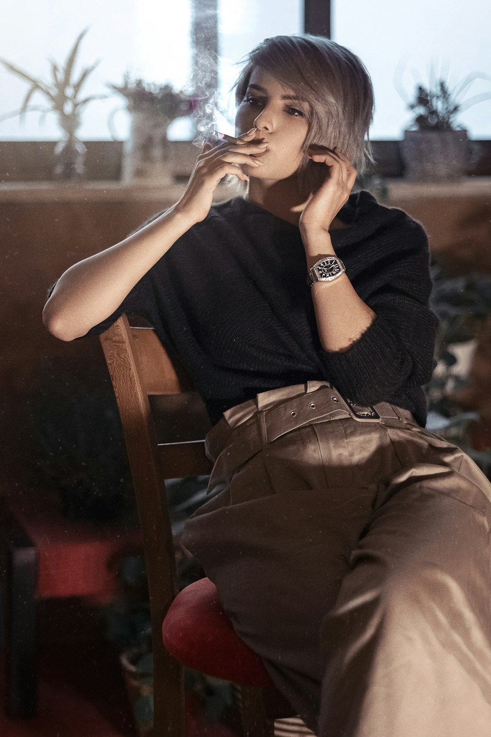 woman in black sleeveless shirt and brown pants sitting on brown wooden chair