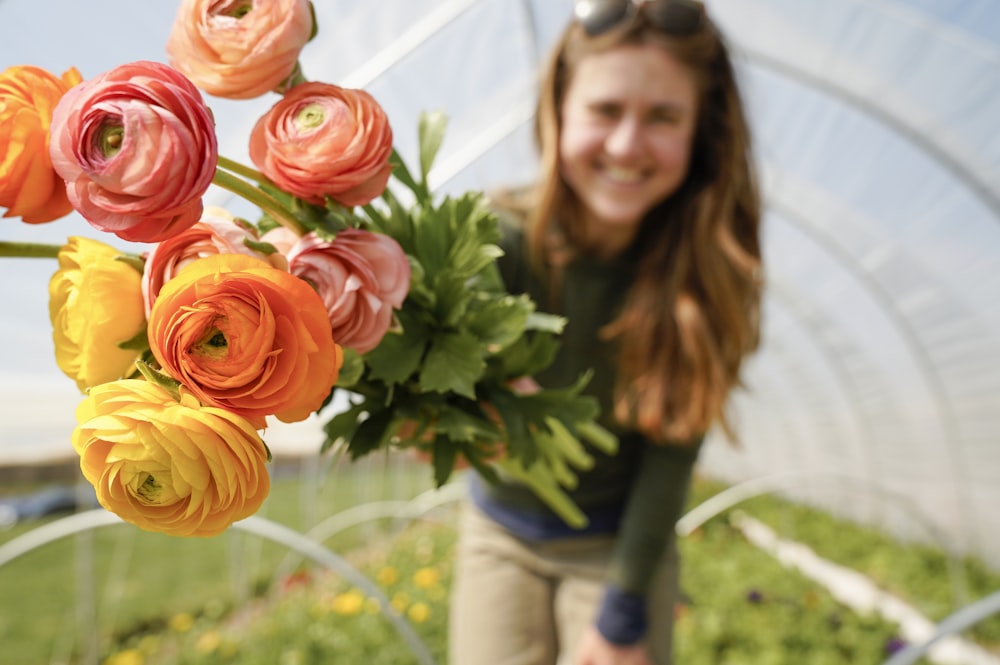 woman in gray long sleeve shirt holding orange flower bouquet