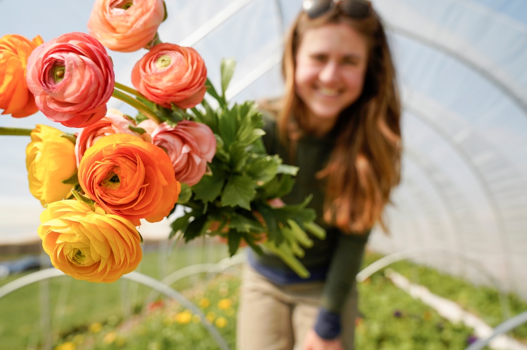 woman in gray long sleeve shirt holding orange flower bouquet