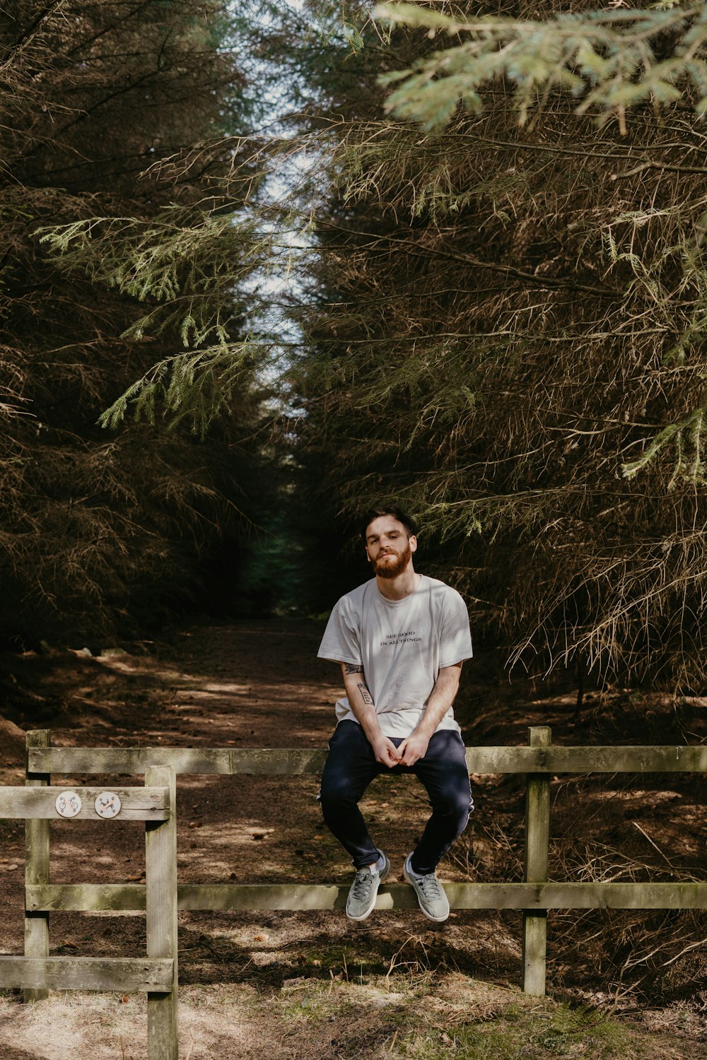 man in white crew neck t-shirt sitting on brown wooden bench