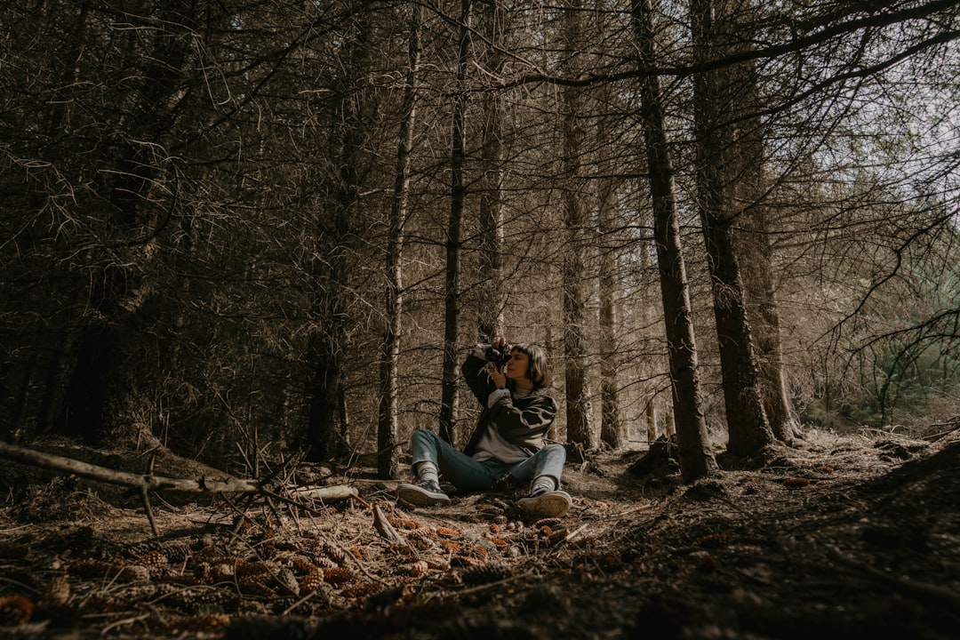 man and woman sitting on brown dried leaves in the woods during daytime