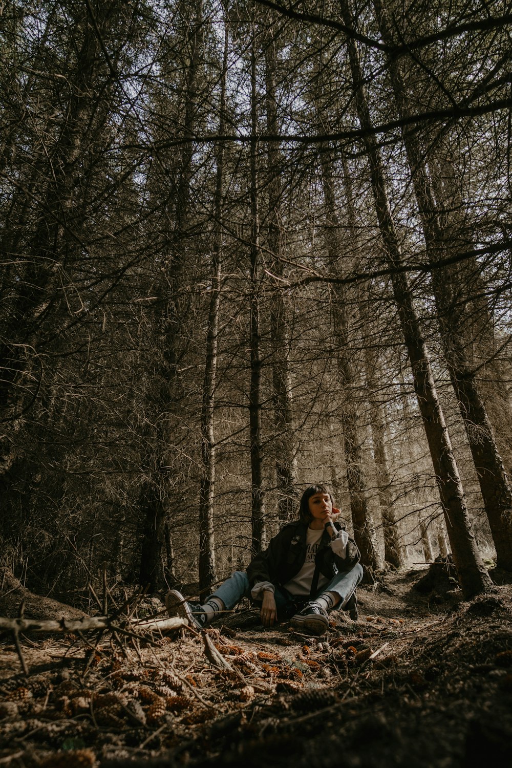 man and woman sitting on ground surrounded by bare trees during daytime