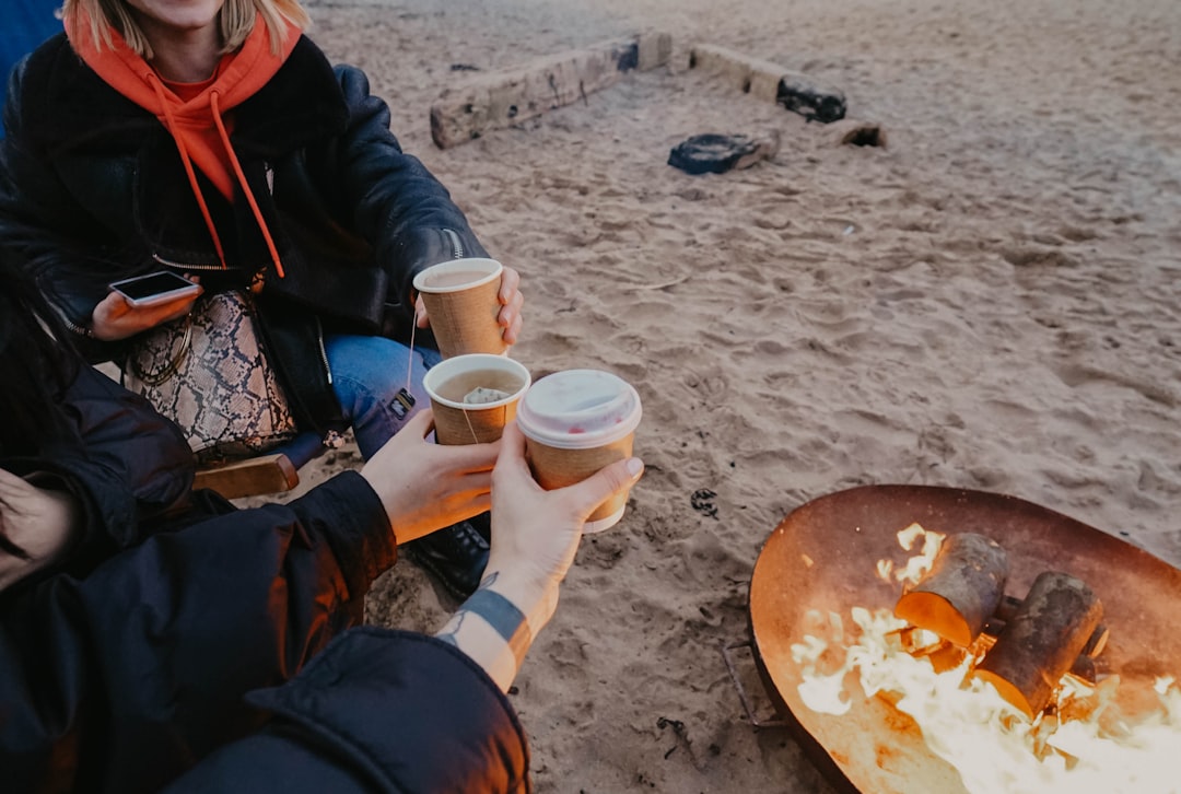 person in black jacket holding white disposable cup