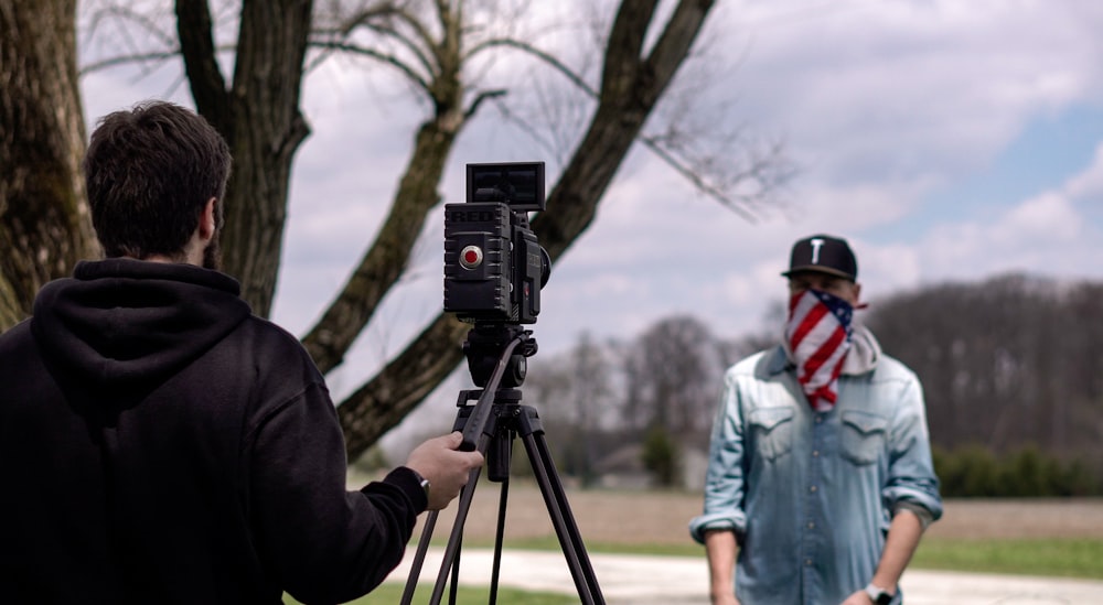 man in black jacket holding black camera