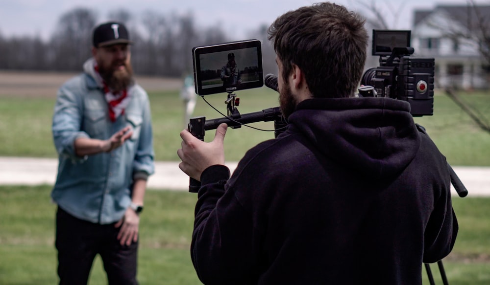 man in black hoodie holding black camera