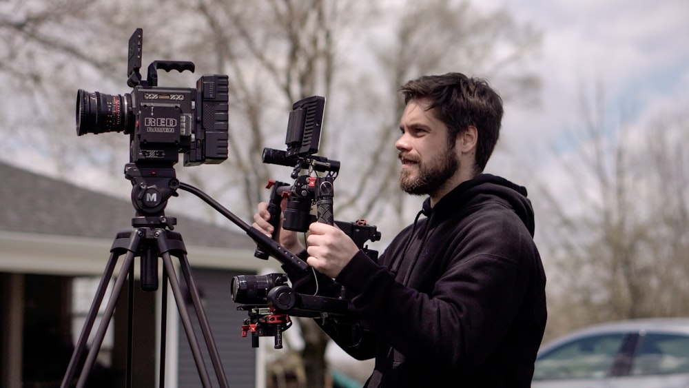 man in black jacket holding black video camera