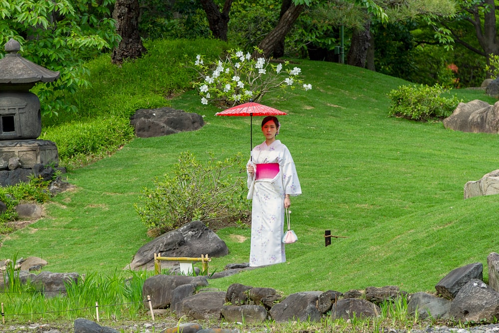 woman in white dress holding umbrella standing on gray rock during daytime