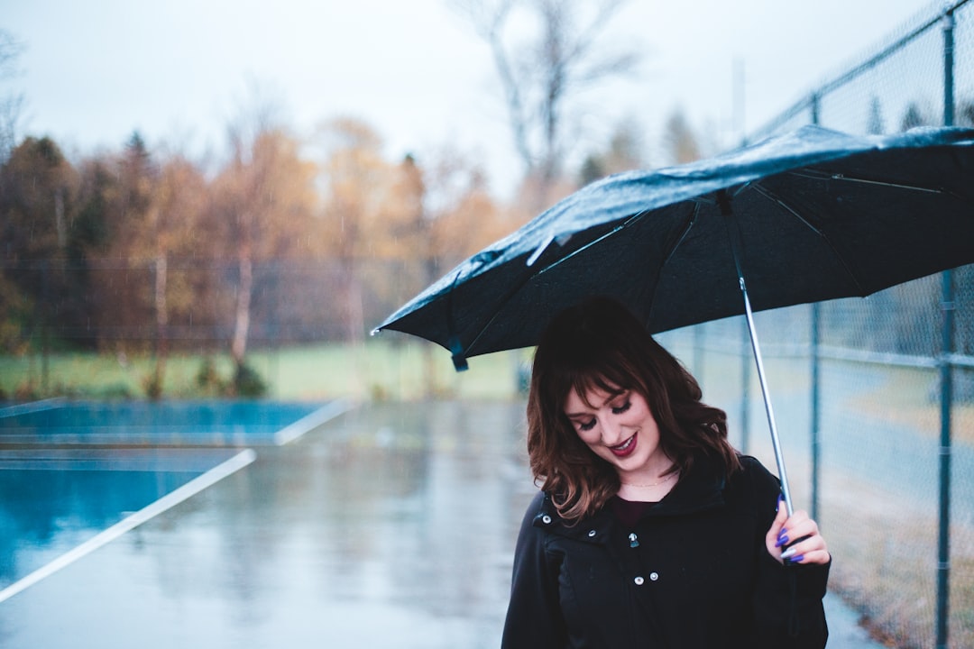 woman in black coat holding umbrella