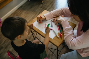 boy in white long sleeve shirt writing on white paper