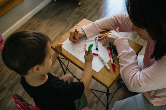 A smiling parent and child filling out a school admission form together at a cozy kitchen table.