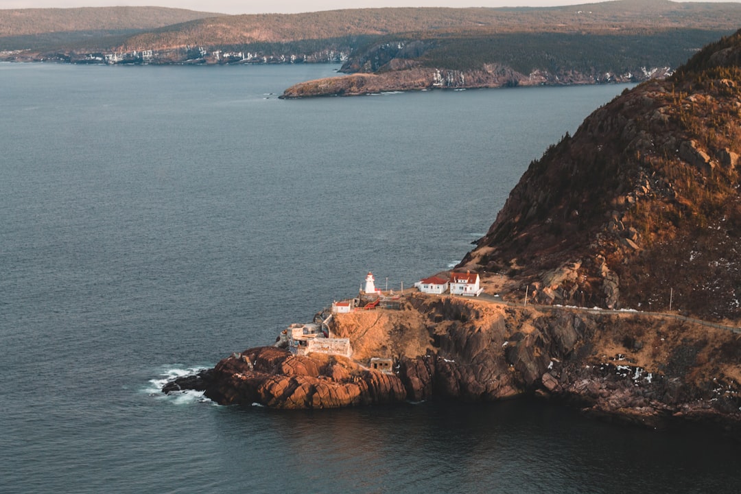 white and brown house on brown rock formation beside sea during daytime