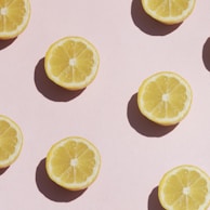 Close-up of fresh lemon slices arranged artfully with shadows playing across a yellow background