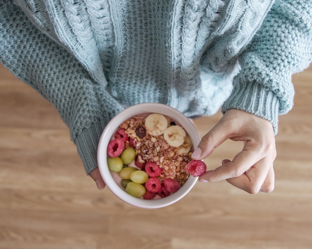 Persona sosteniendo un cuenco de cerámica blanca con frijoles rojos y amarillos