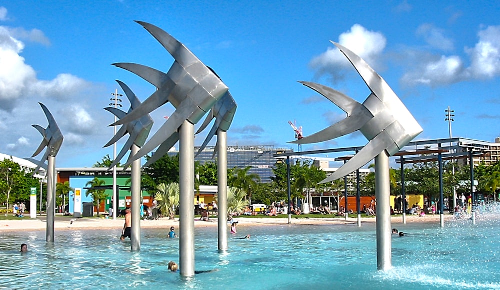 people walking on park with gray concrete fountain during daytime