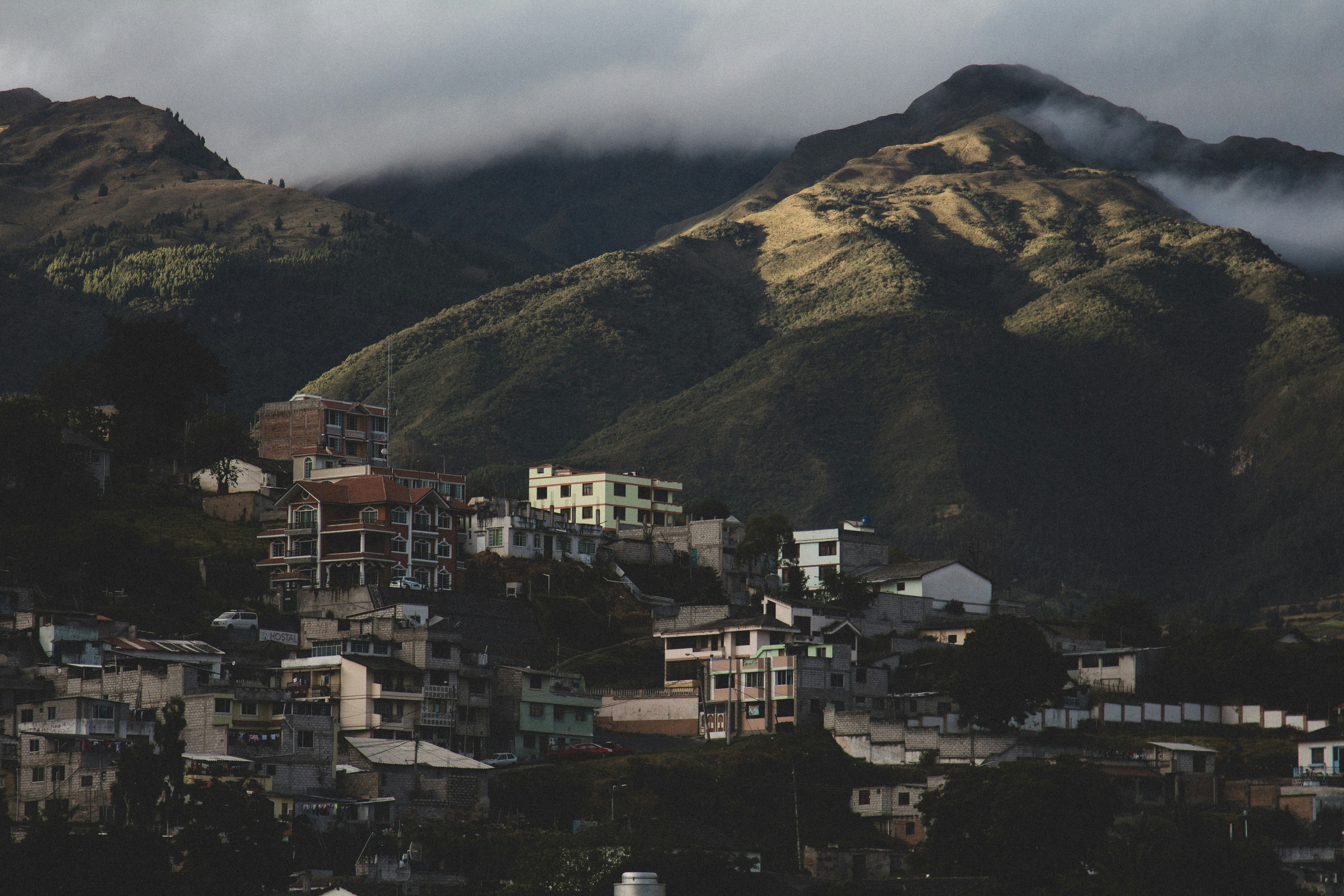 white and brown concrete buildings on green mountain - Otavalo