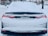 A snow-covered car parked on a residential street, with snow blanketing the rear windshield and trunk, partially obscuring the car's logo and license plate.
