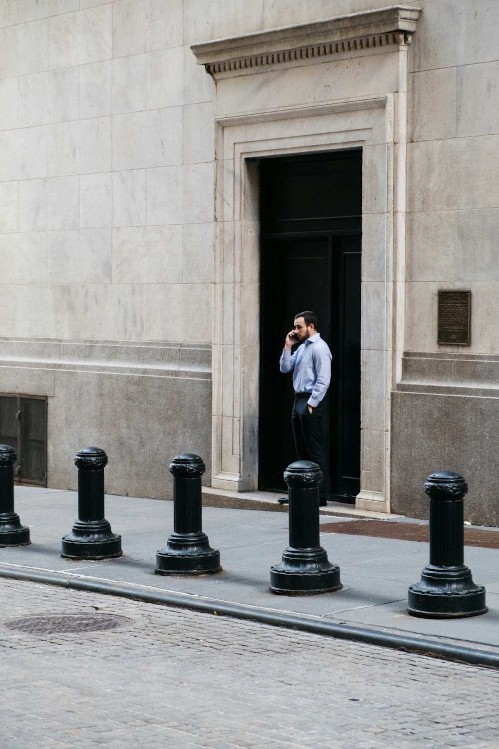 man in black suit standing near black metal stand