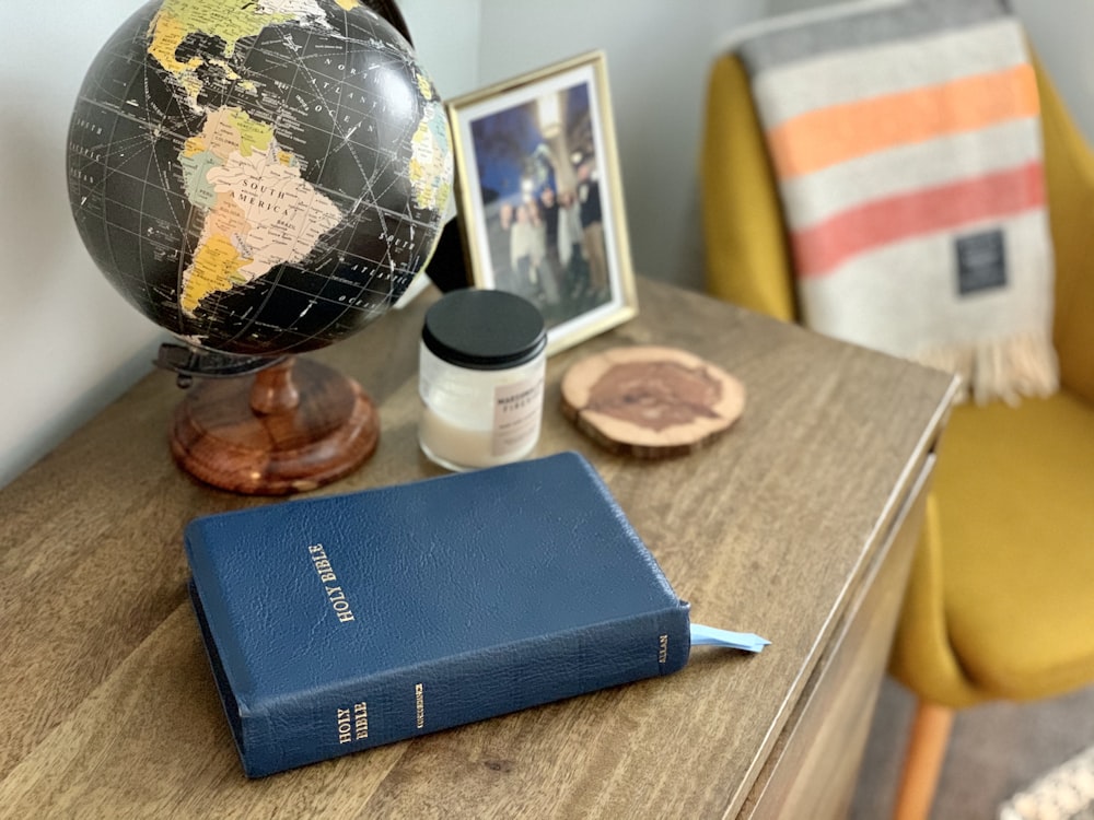 blue book beside blue click pen on brown wooden table