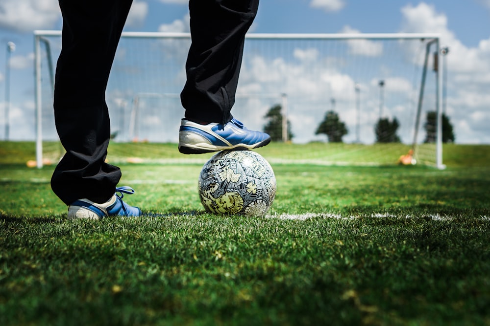 person in black pants and blue and white nike soccer ball on green grass field during