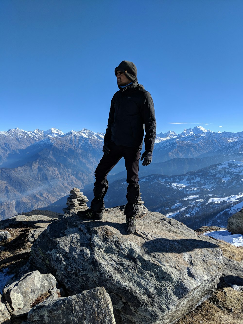 man in black jacket standing on rock formation during daytime