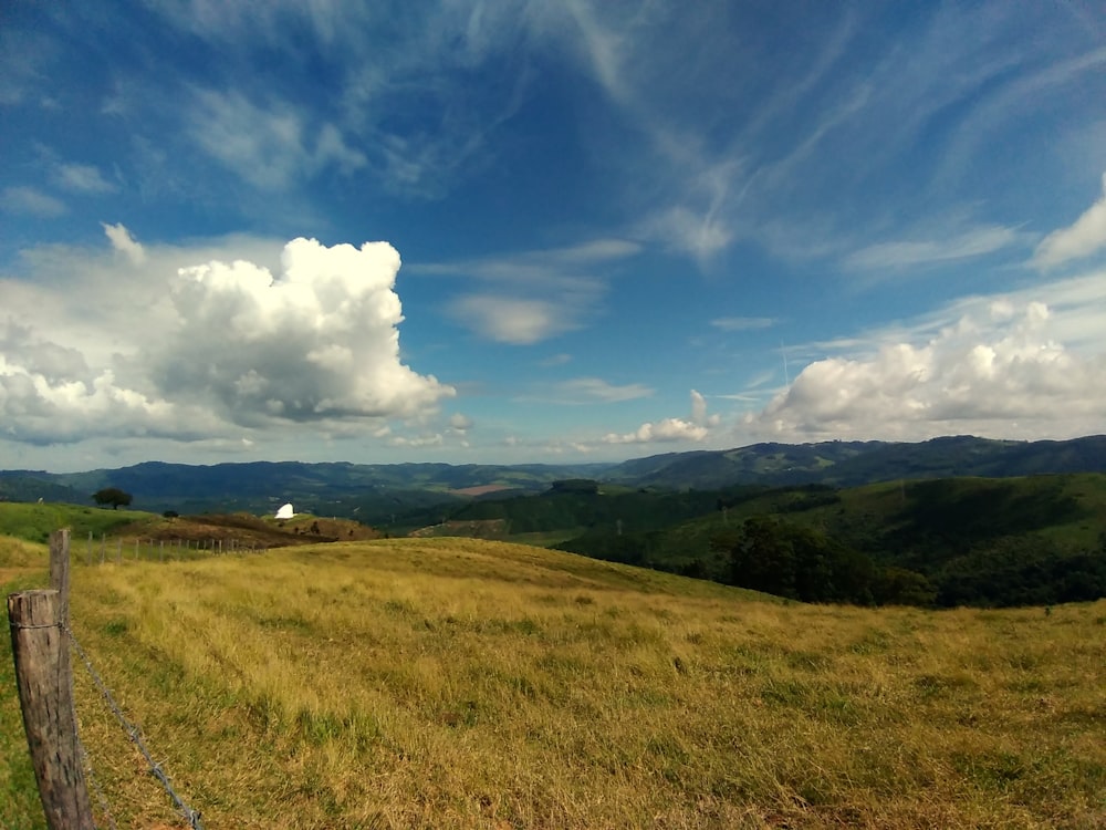 green grass field under blue sky and white clouds during daytime