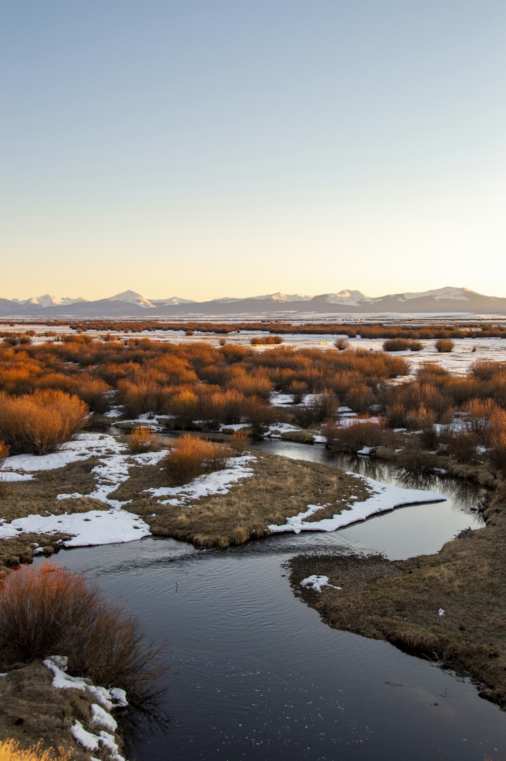 a river running through a dry grass covered field