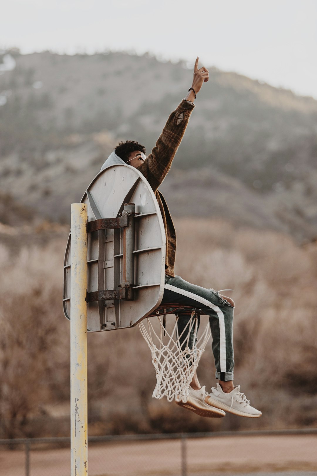person in brown jacket holding basketball hoop during daytime