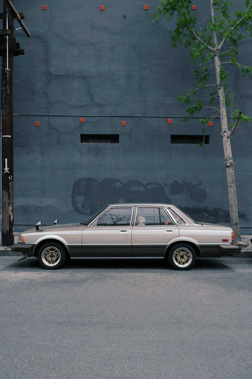 灰色のコンクリートの建物の横に駐車された白と茶色のクラシックカー