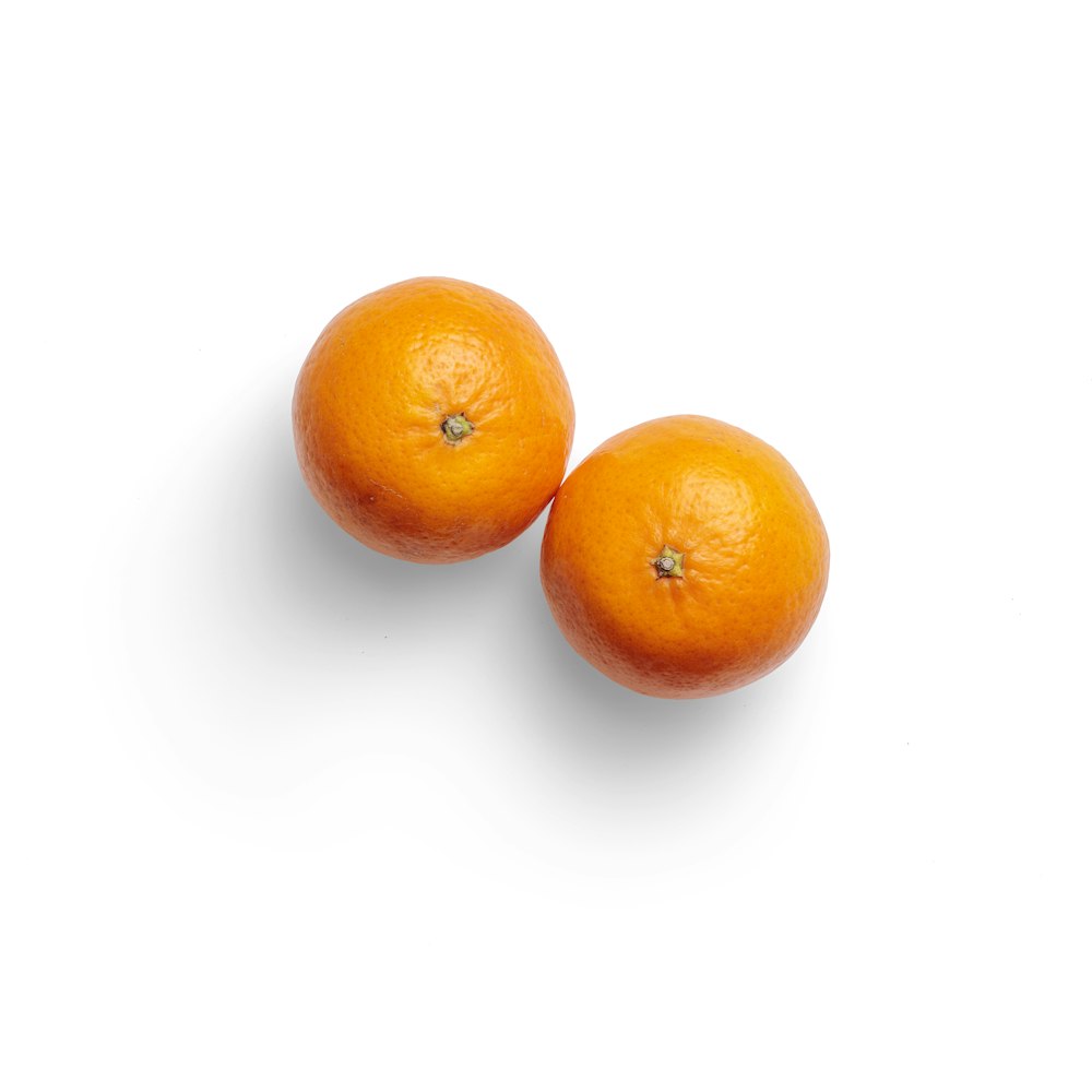 2 frutos anaranjados sobre superficie blanca
