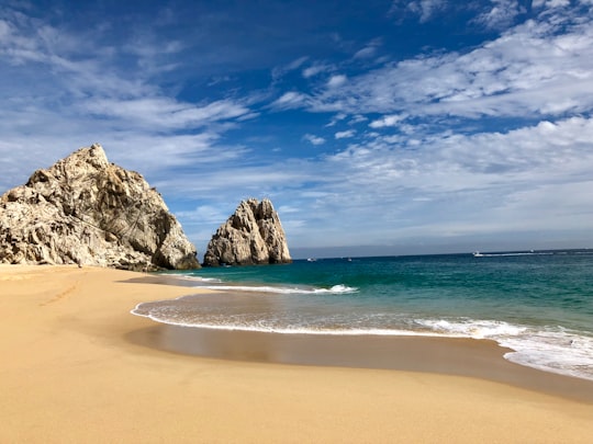 brown rock formation on sea shore under blue sky and white clouds during daytime in Los Cabos Mexico