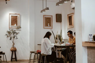 Wide shot of the café interior with spaced seating and customers quietly working on their laptops.