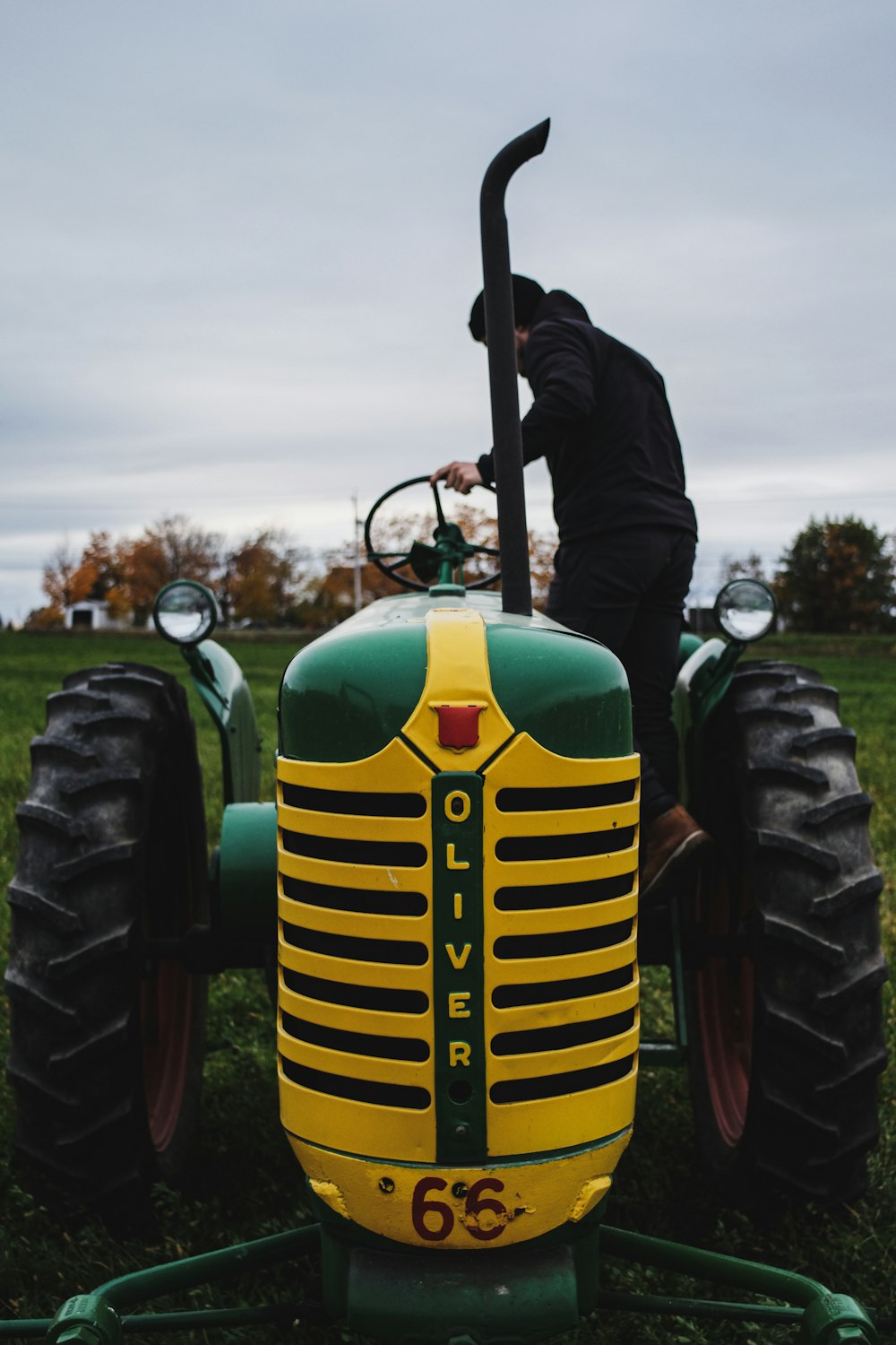 homme en veste noire et pantalon debout sur le tracteur vert pendant la journée