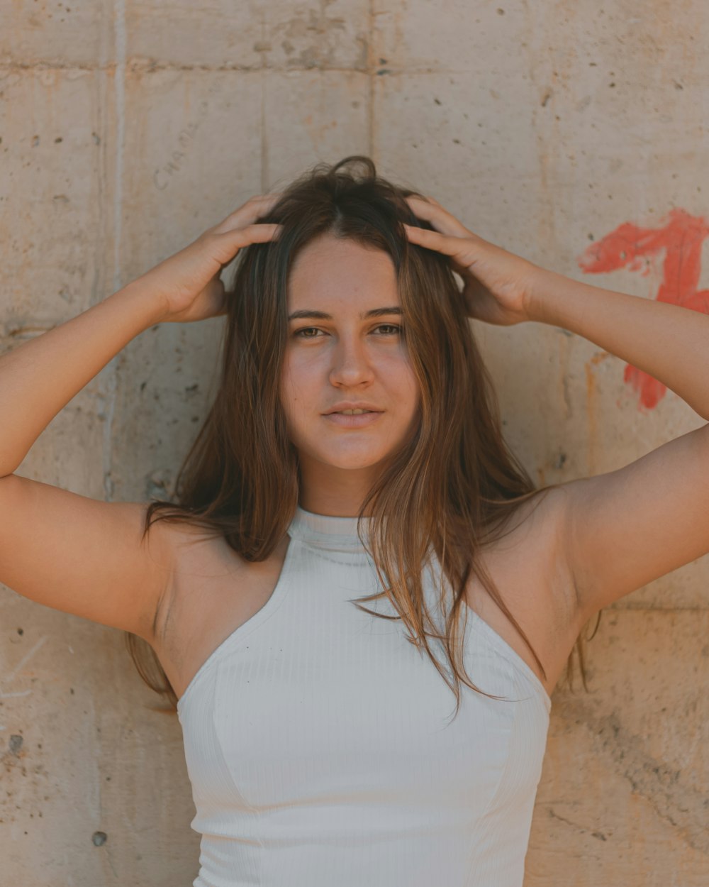 woman in white tank top holding her hair