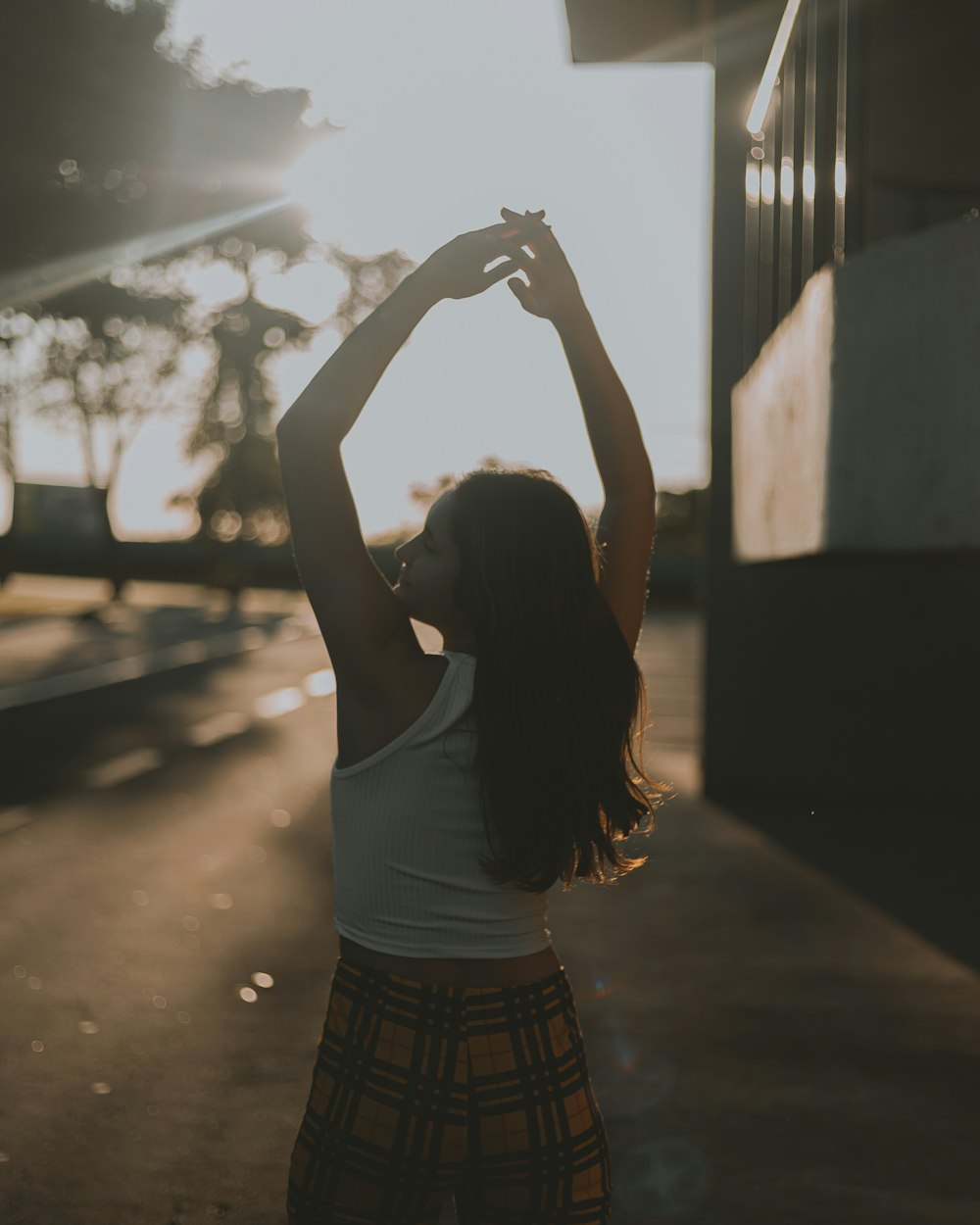 woman in white tank top and black and white plaid skirt raising her hands