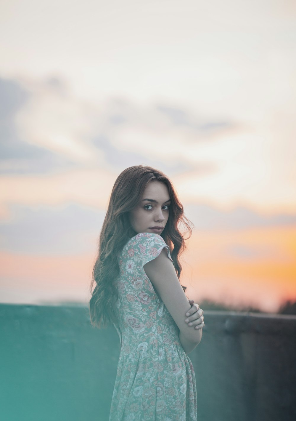 woman in teal long sleeve shirt standing near body of water during daytime