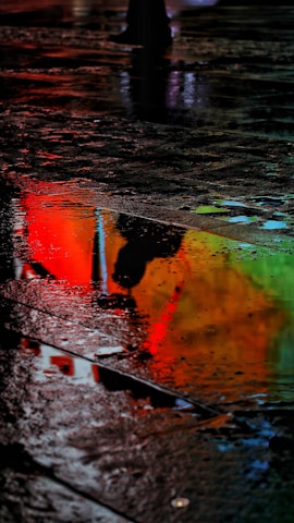 Reflections of a bustling market in a rain-soaked pavement in Manila, colors muted yet vivid.
