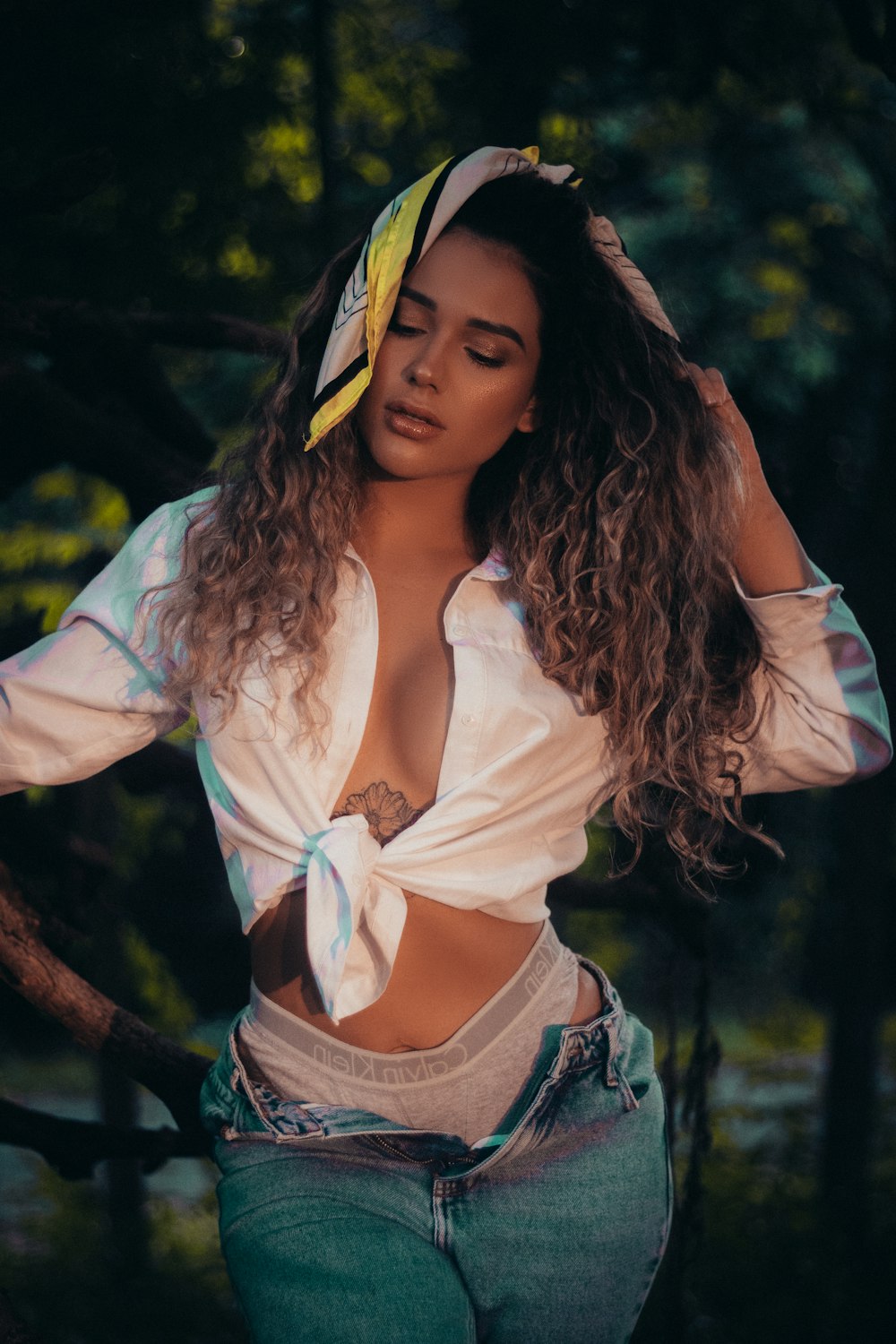 woman in white dress shirt and blue denim shorts standing near green trees during daytime